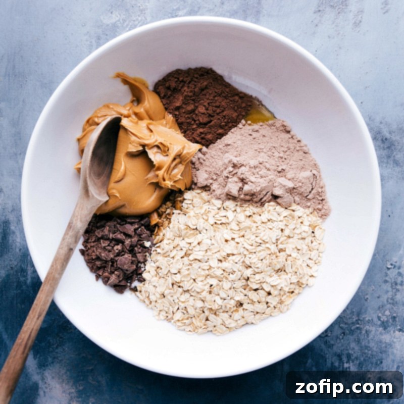 All the dry and wet ingredients for chocolate peanut butter energy bites beautifully displayed in a bowl, ready to be combined and mixed for a delicious snack.