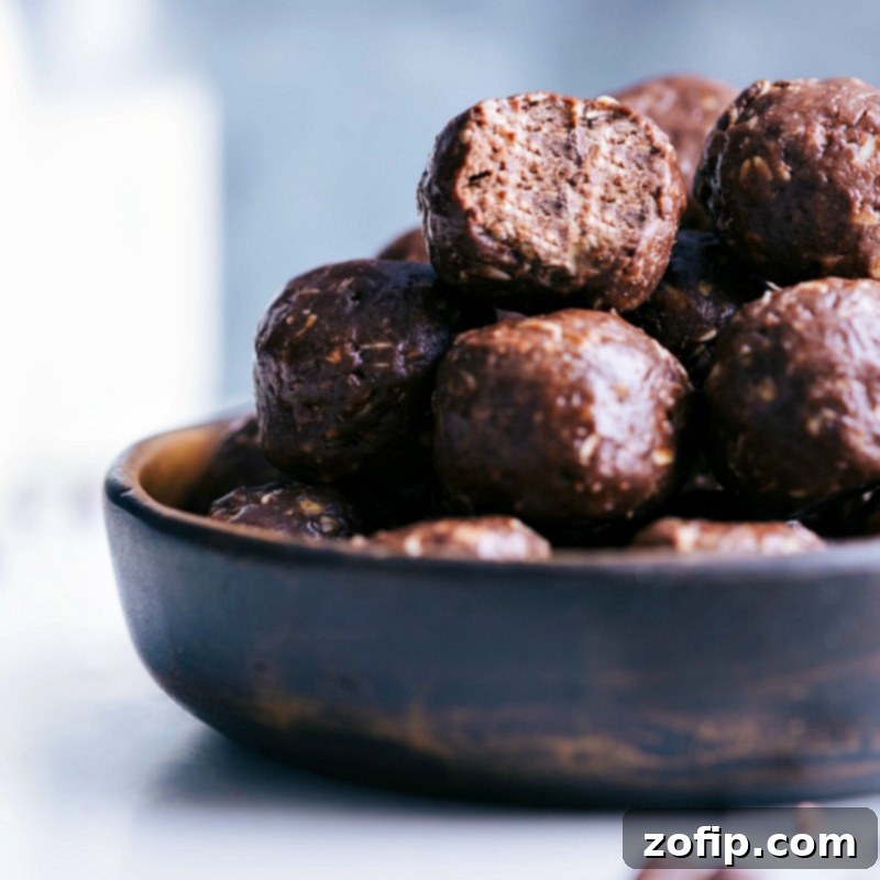 A rustic bowl overflowing with tempting chocolate energy bites, with one bite partially eaten, inviting viewers to indulge in the rich, wholesome snack.
