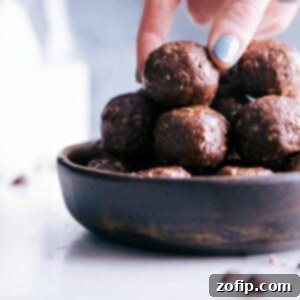 Bowl filled with delectable chocolate energy bites, a hand reaching in to grab a delightful bite.