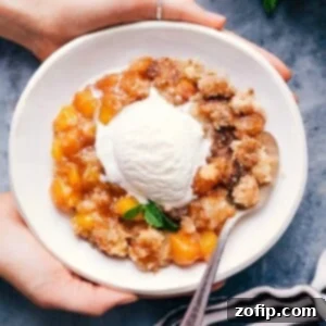 Sweet and delicious peach cobbler in a bowl with a scoop of vanilla ice cream on top.