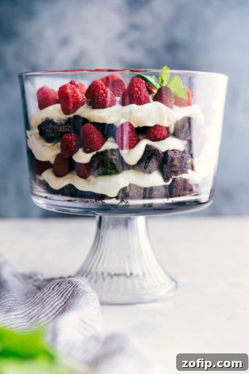 Elegant Brownie Trifle with Layers of Brownies, Fruit, and Cream, Ready for Enjoyment A stunning brownie trifle displaying layers of fudgy brownies, fresh raspberries, and luscious cream filling, artfully arranged in a clear glass dish.