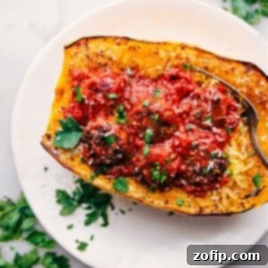 Finished spaghetti squash filled with marinara and meatballs, topped with fresh cheese and herbs.