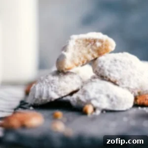 Stack of Mexican Wedding Cookies with a bite taken out of one, showing the fluffy interior.