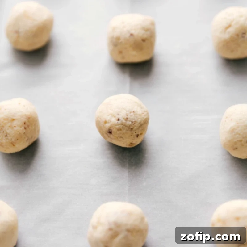 Perfectly rolled dough balls arranged on a silicone-lined sheet pan, ready for baking into Mexican Wedding Cookies.