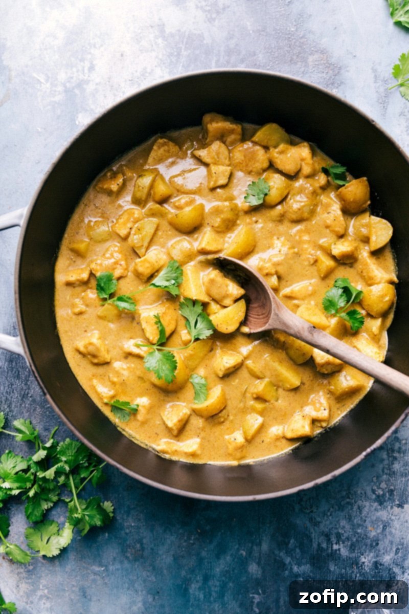 A beautifully plated dish of Thai Yellow Chicken Curry, featuring succulent chicken, tender baby gold potatoes, and green beans bathed in a creamy, golden coconut sauce. Garnished with fresh cilantro, ready to be enjoyed.