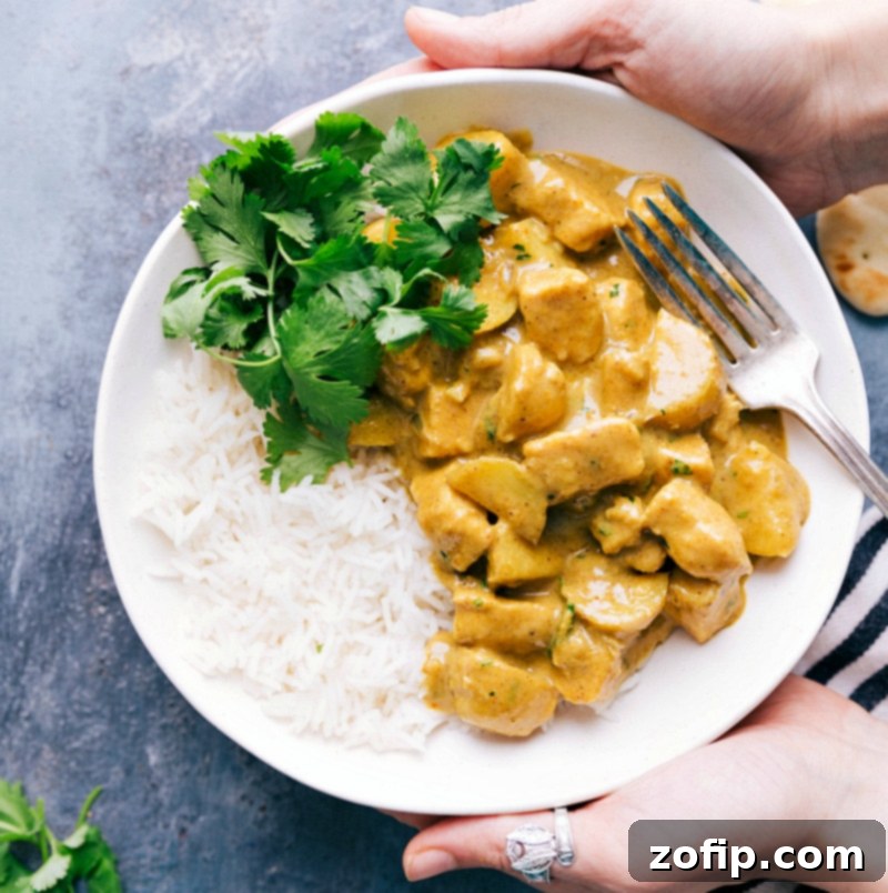 A vibrant and comforting bowl of Thai Yellow Chicken Curry, served over perfectly cooked rice and garnished with fresh green herbs. The rich, golden sauce, tender chicken, and soft potatoes create a hearty and inviting meal.