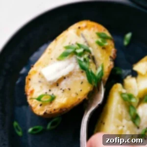 Perfect Fluffy Baked Potatoes 3 Freshly baked potatoes topped with melting butter and sprinkled with vibrant green chives, ready to be eaten.