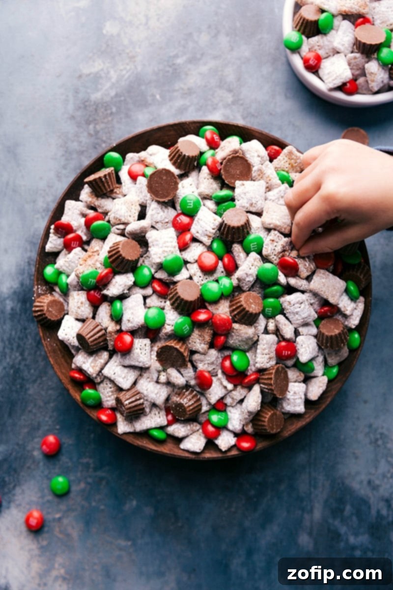 Festive Reindeer Chow: A Holiday Favorite Finished reindeer chow with Christmas-colored M&M's and mini Reese's peanut butter cups on top, ready to be served.