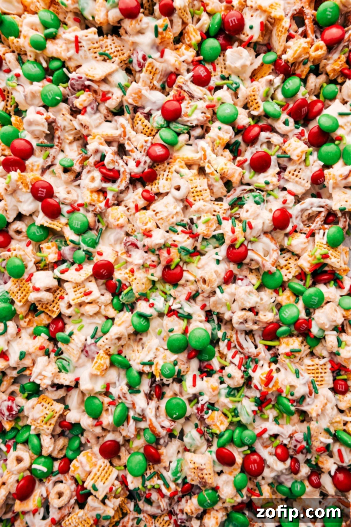 Festive Christmas Snack Mix with vibrant red and green M&M's and sparkling sprinkles, coated in white chocolate, ready to be enjoyed.