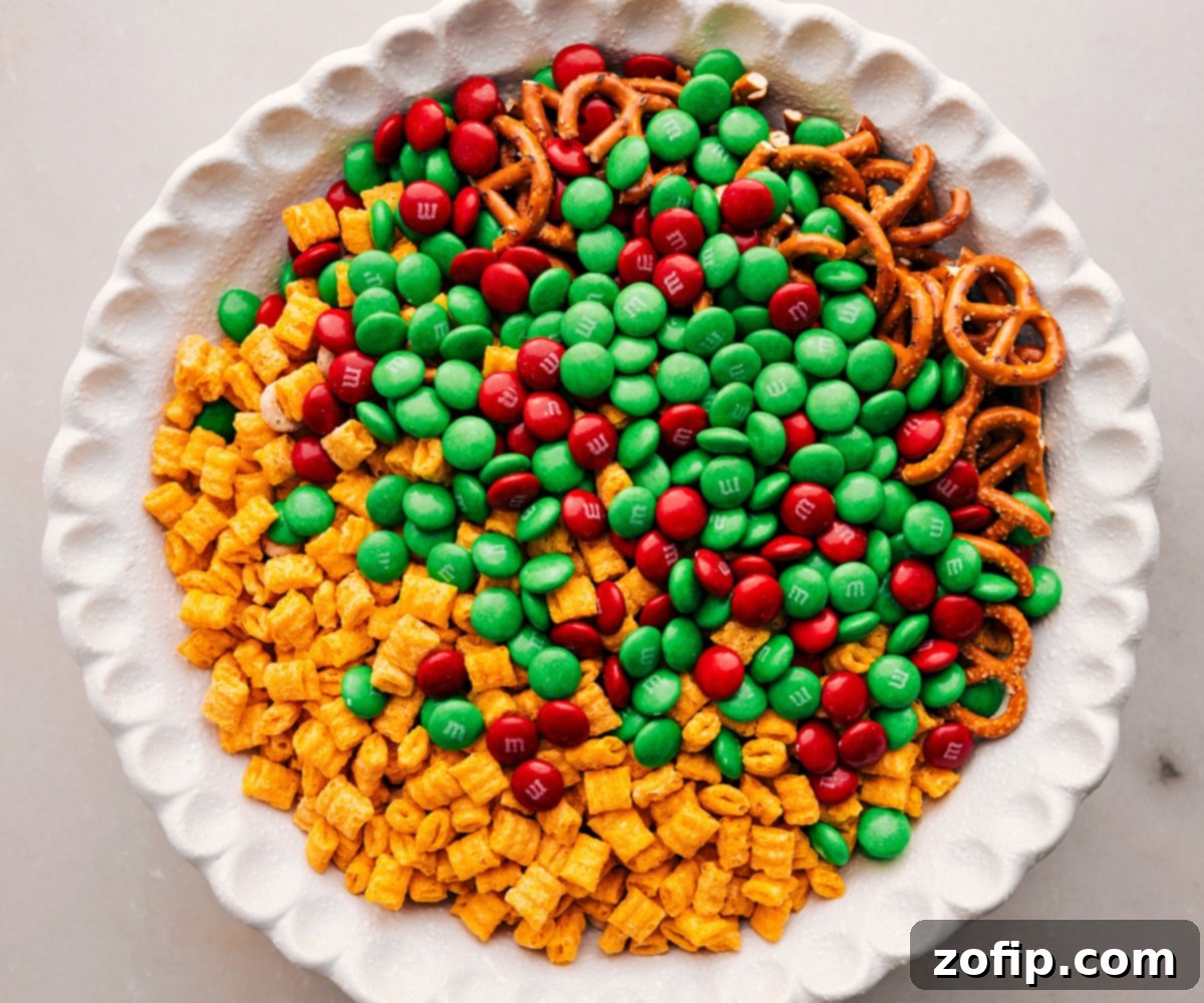 All dry ingredients for the Christmas Snack Mix, including cereals, pretzels, and M&M's, are combined in a large mixing bowl before the chocolate is added.