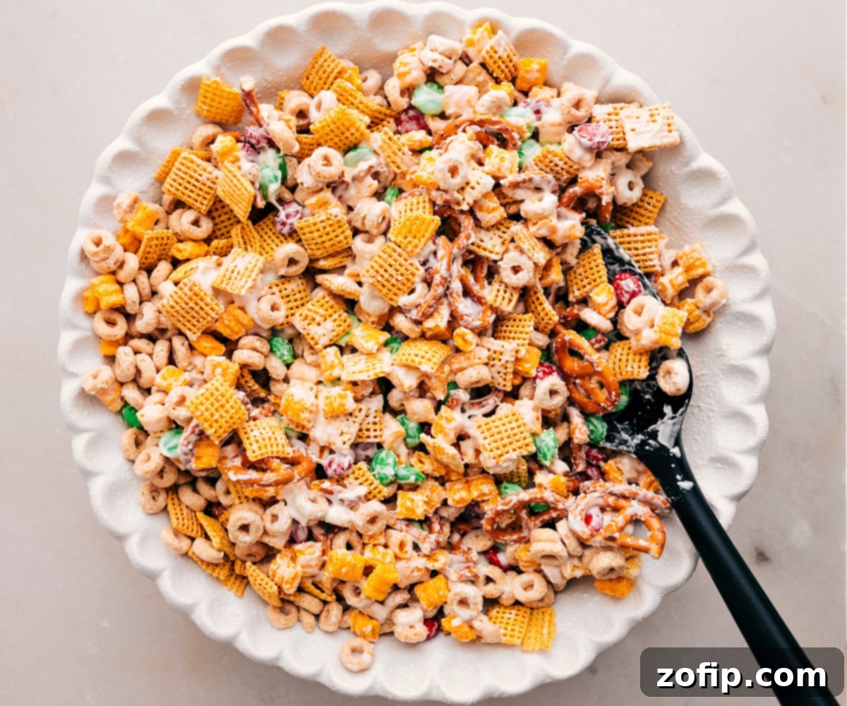 A bowl filled with freshly made Christmas Snack Mix, coated in white chocolate and studded with festive M&M's and sprinkles, ready for serving.