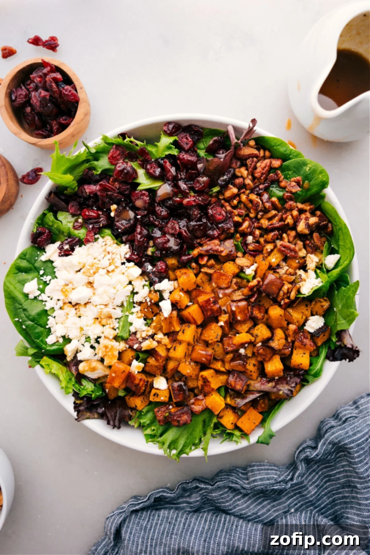 The Best Thanksgiving Salad Recipe: A Fresh Holiday Side A vibrant Thanksgiving Salad in a large bowl, featuring roasted butternut squash, dark green spinach, red cranberries, and crumbled feta, dressed and ready to be served.