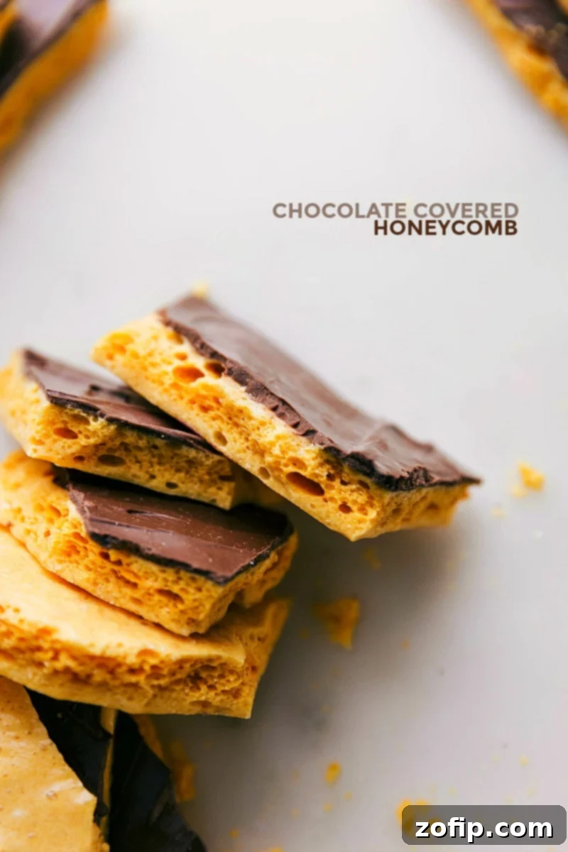 Piles of golden homemade Honeycomb Candy pieces, some drizzled with chocolate, on a white background.
