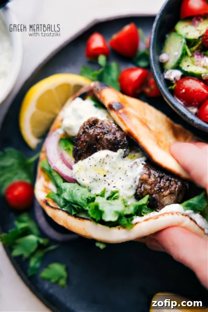 Platter of golden-brown Greek Meatballs (Keftedes) served in pita bread with tzatziki and fresh vegetables.