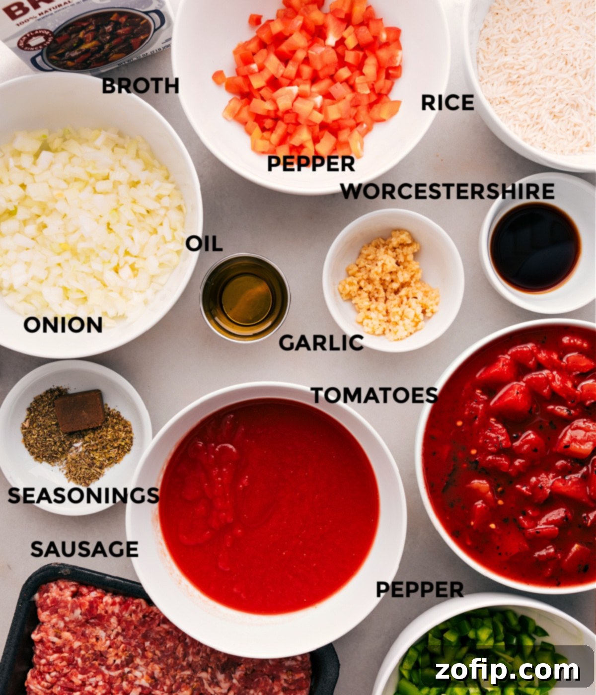 All the fresh ingredients for homemade stuffed pepper soup laid out: colorful bell peppers, onion, garlic, canned diced tomatoes, marinara, beef broth, ground Italian sausage, cooked rice, and a selection of herbs and spices.