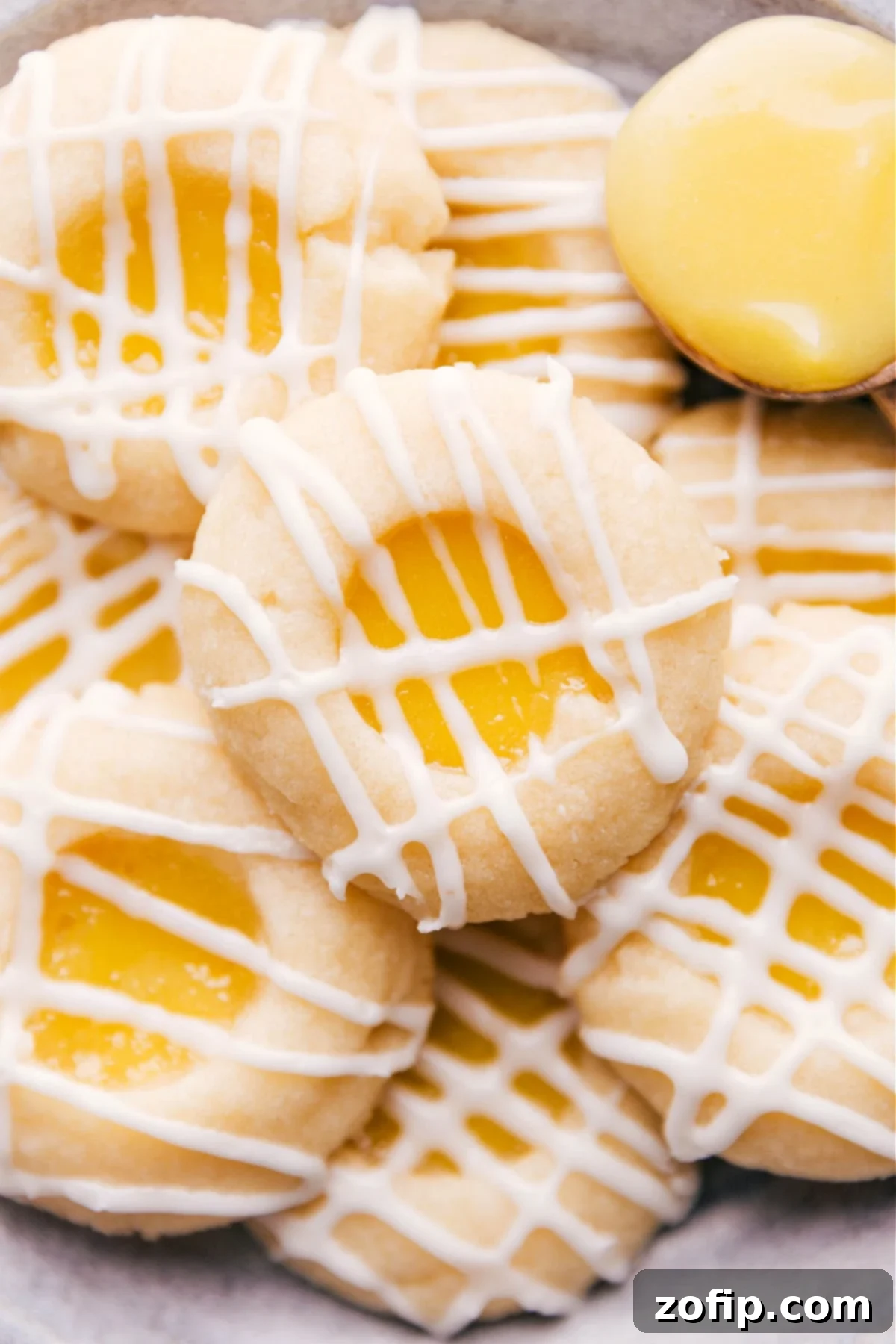 Soft, buttery cookies filled with tangy lemon curd and topped with a light vanilla-almond glaze, arranged beautifully on a serving plate.