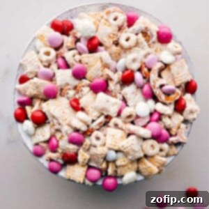 A close-up shot of Valentine Snack Mix in a bowl, highlighting the colorful M&M's, pretzels, and cereal pieces coated in white chocolate.