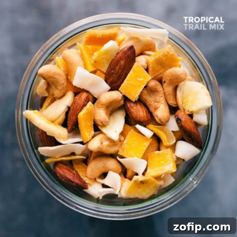 Delicious and healthy tropical trail mix full of nuts, dried fruits, and coconut, showcased beautifully in a clear glass jar.