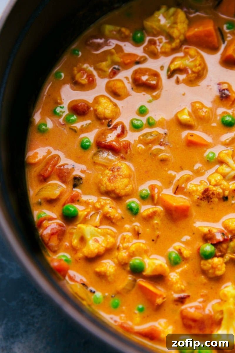 Vegetable Curry Perfection: Rich and Flavorful with an Array of Veggies A hearty pot of vegetable curry brimming with colorful vegetables and simmered in a coconut curry broth, ready to be served.