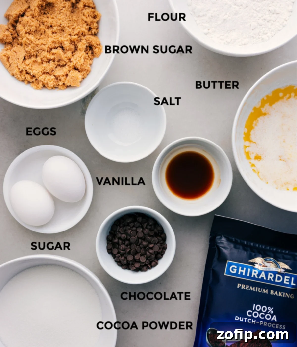 Ingredients In This Brownie Recipe All the essential ingredients for the fudgy brownie recipe—melted butter, both white and brown sugars, eggs, vanilla, flour, Dutch-processed cocoa powder, salt, and mini chocolate chips—are neatly laid out on a countertop, ready for mixing.