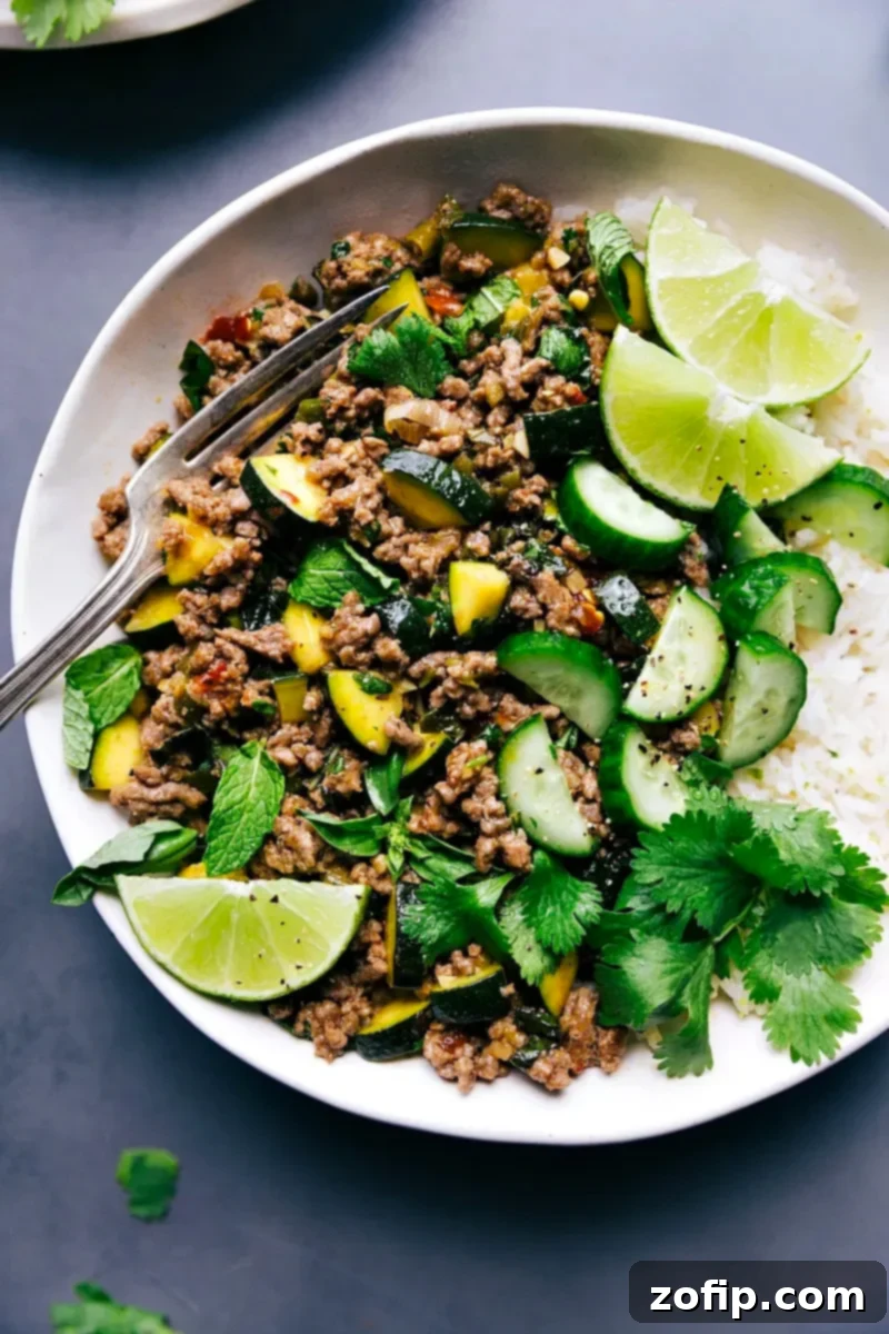 Flavorful Beef Larb with Coconut Rice, Garnished with Lime and Fresh Herbs A vibrant plate of Beef Larb served with fluffy white rice, garnished with fresh lime wedges and sprigs of cilantro and mint.