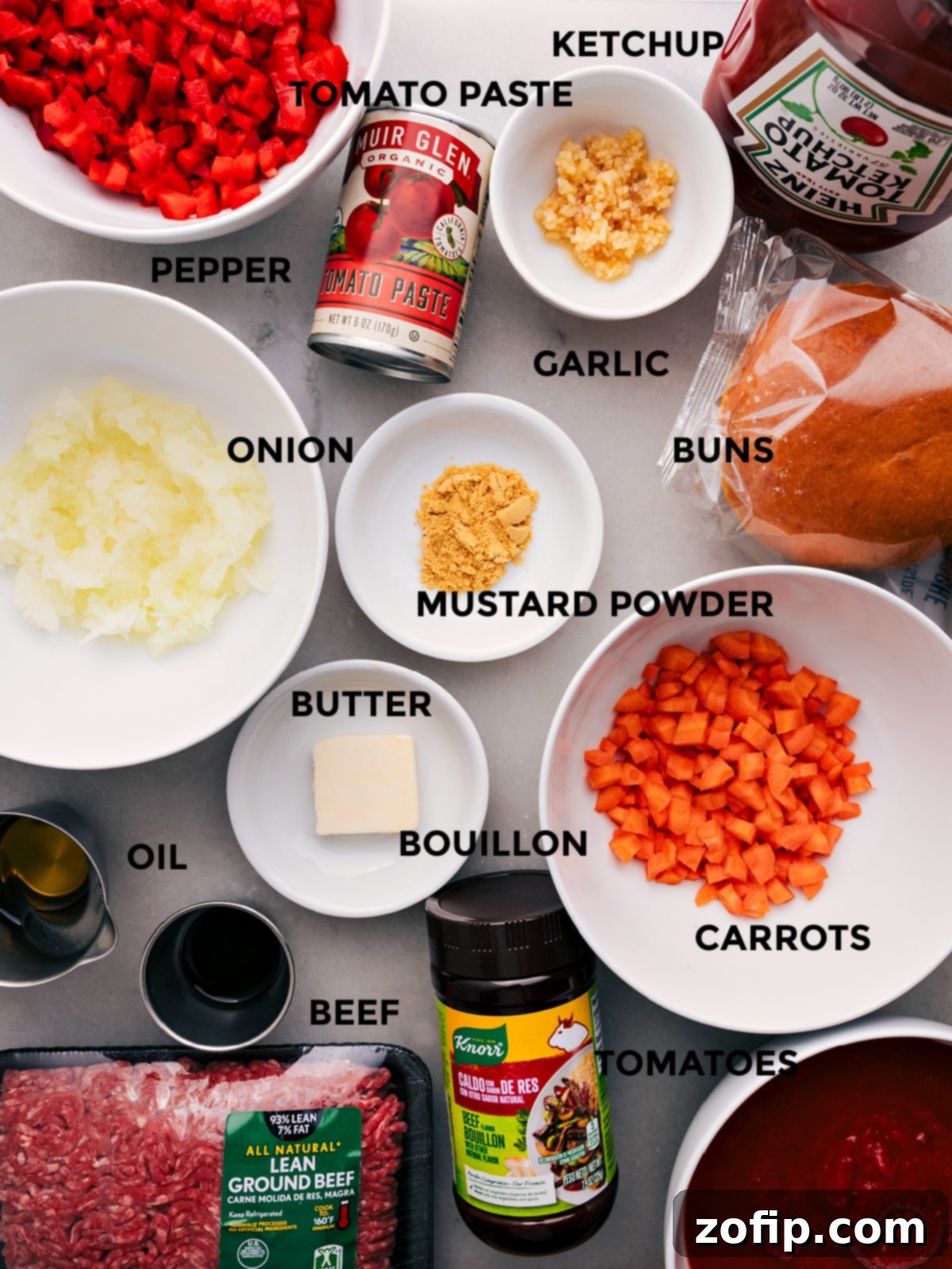 Key Ingredients for Delicious Sloppy Joes: From Fresh Veggies to Flavorful Spices All the essential ingredients for this Sloppy Joes recipe are meticulously prepped and laid out: vibrant ketchup, freshly ground pepper, concentrated tomato paste, soft hamburger buns, various seasonings, diced onion, rich butter, savory beef bouillon, lean ground beef, and ripe crushed tomatoes. Ready for easy assembly.