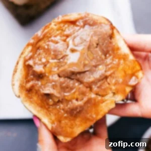 Slice of honey whole wheat bread generously spread with honey butter, ready for a delightful snack.