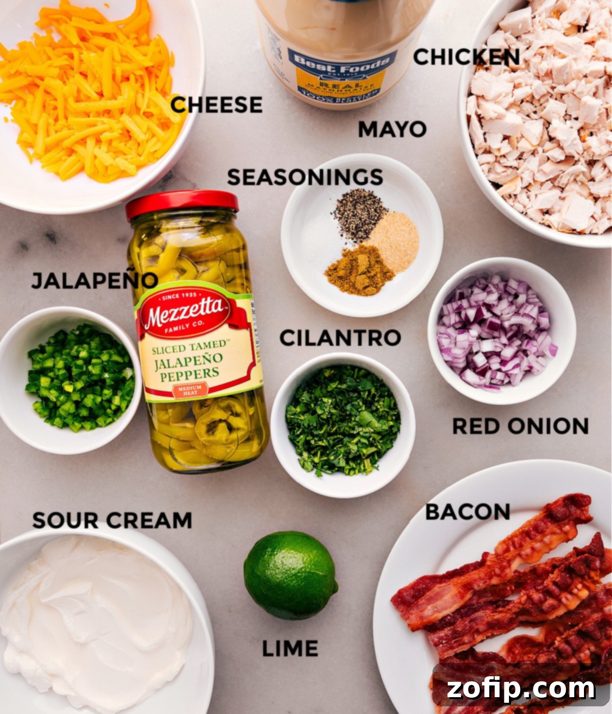 All the ingredients for this recipe are prepped for easy assembly, including cheese, mayo, eggs, seasonings, meat, and sour cream.
