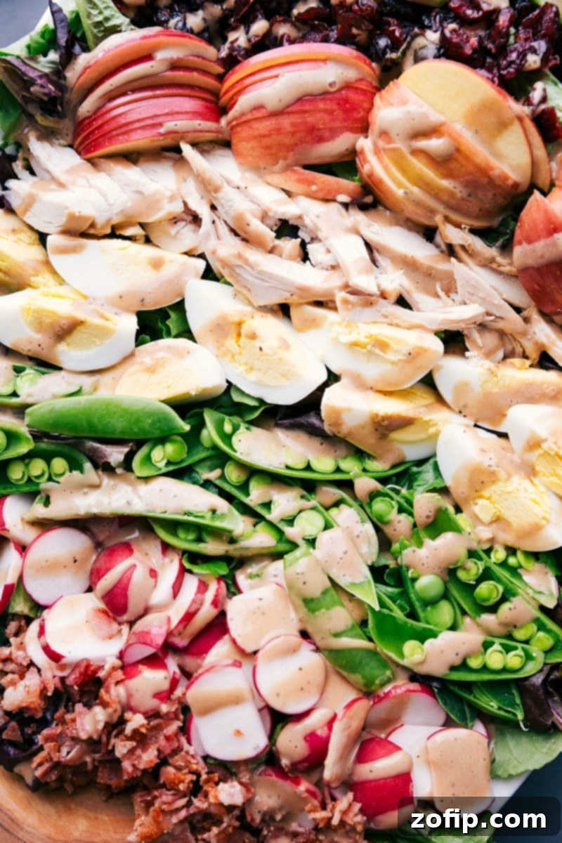 Completed salad, artfully arranged to highlight apples, chicken, hard-boiled eggs, sugar snap peas, and radishes.