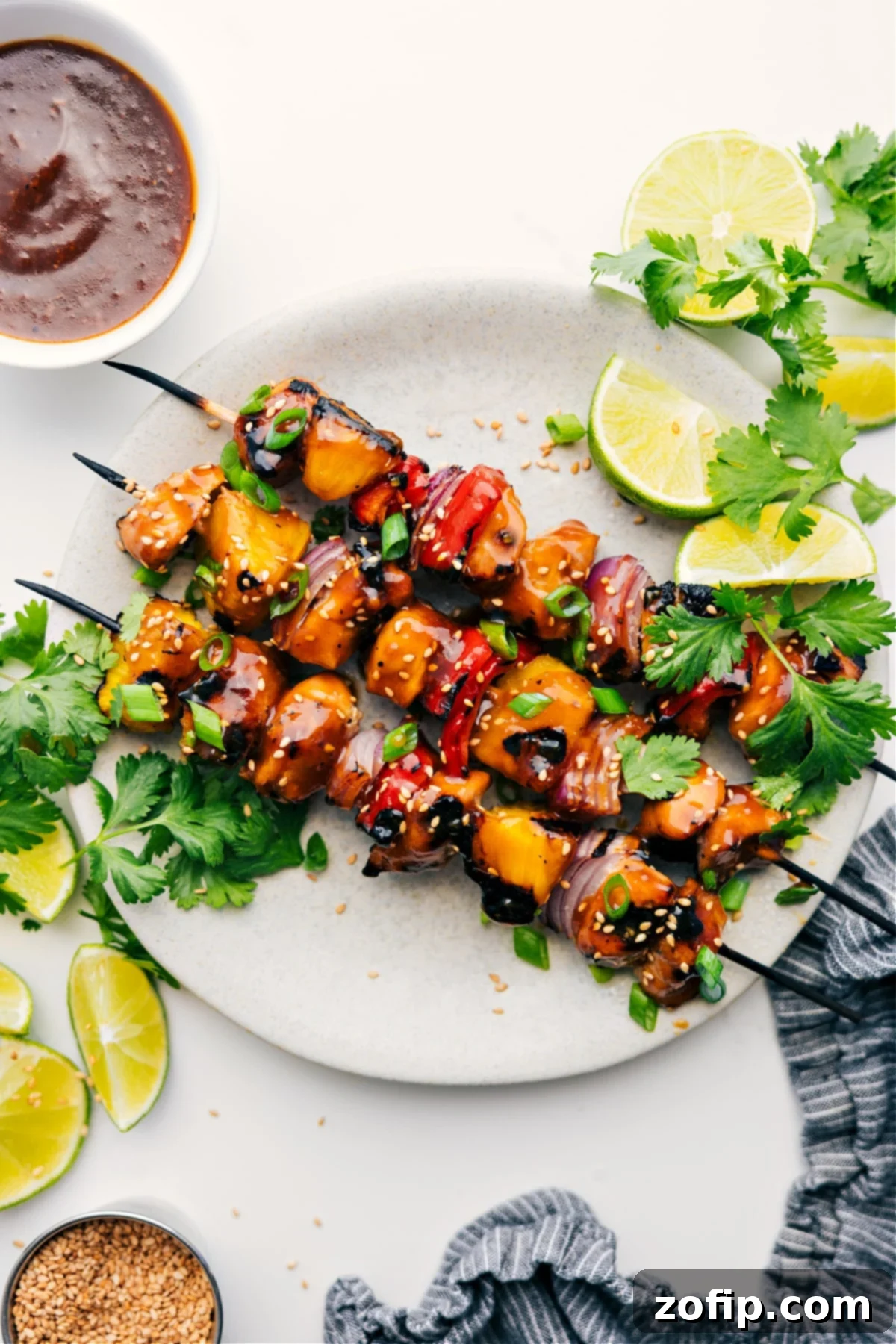 Grilled Teriyaki Chicken Skewers served with lime wedges, fresh cilantro, and a side of dipping sauce, ready to be enjoyed.