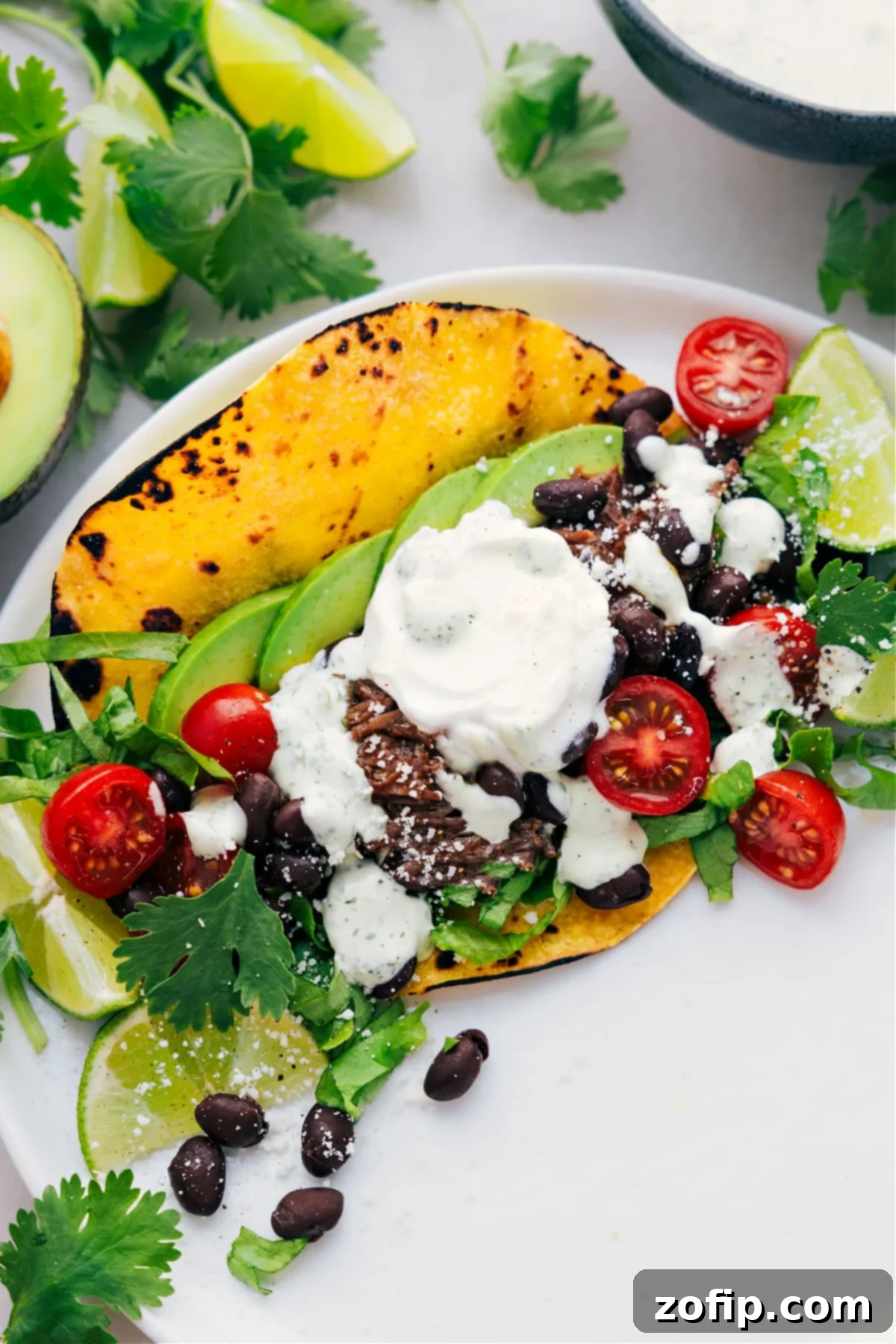 Shredded Beef Tacos on a plate with all the delicious toppings, ready to be enjoyed.