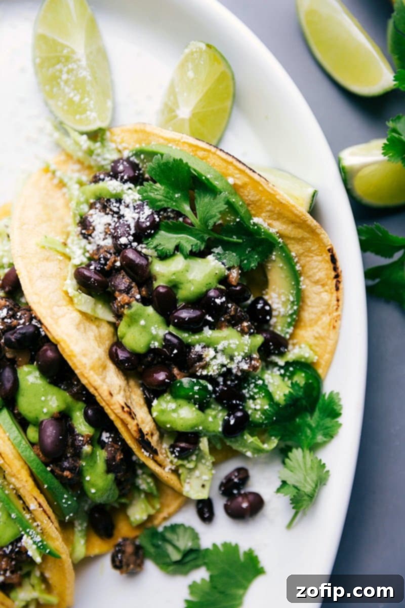 Delicious Black Bean Tacos drizzled with homemade cilantro sauce, garnished with fresh cilantro and lime wedges, ready to eat.