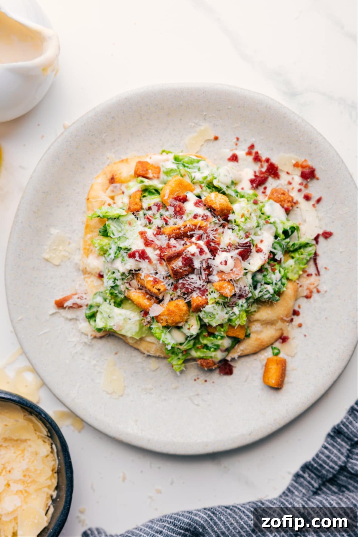 A delicious Caesar Salad Pizza on a plate, topped with fresh romaine, parmesan, and a creamy Caesar dressing, ready to be enjoyed.