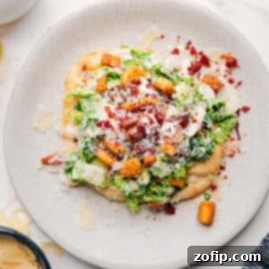 Caesar Salad Pizza with chicken, fresh romaine, parmesan, and a creamy Caesar dressing on a naan base.