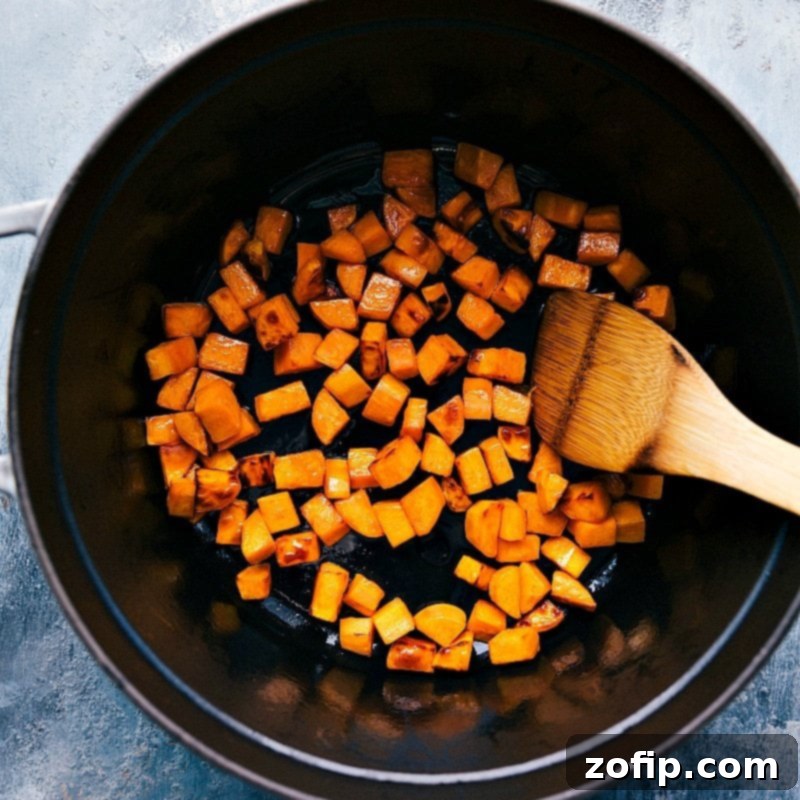 Cooking Sweet Potatoes for Sweet Potato Quinoa Chili - A Vital Step in the Recipe Small, uniformly cut sweet potato cubes gently cooking in a large pot, beginning to soften and develop their sweetness, a key preliminary step in preparing this hearty sweet potato quinoa chili.