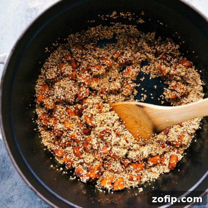 Adding Quinoa to Sweet Potatoes in Pot - Progressing with Sweet Potato Quinoa Chili Recipe Raw quinoa grains are carefully added to the pot, joining the already sautéed and seasoned sweet potatoes. This moment marks the fusion of core ingredients for the flavorful sweet potato quinoa chili recipe.