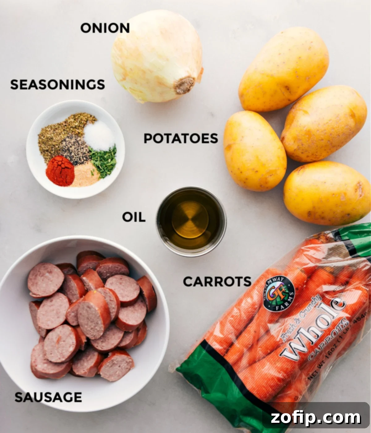 All the ingredients in this recipe including sausage, seasonings, onion, potatoes, and carrots being prepped for easy assembly.