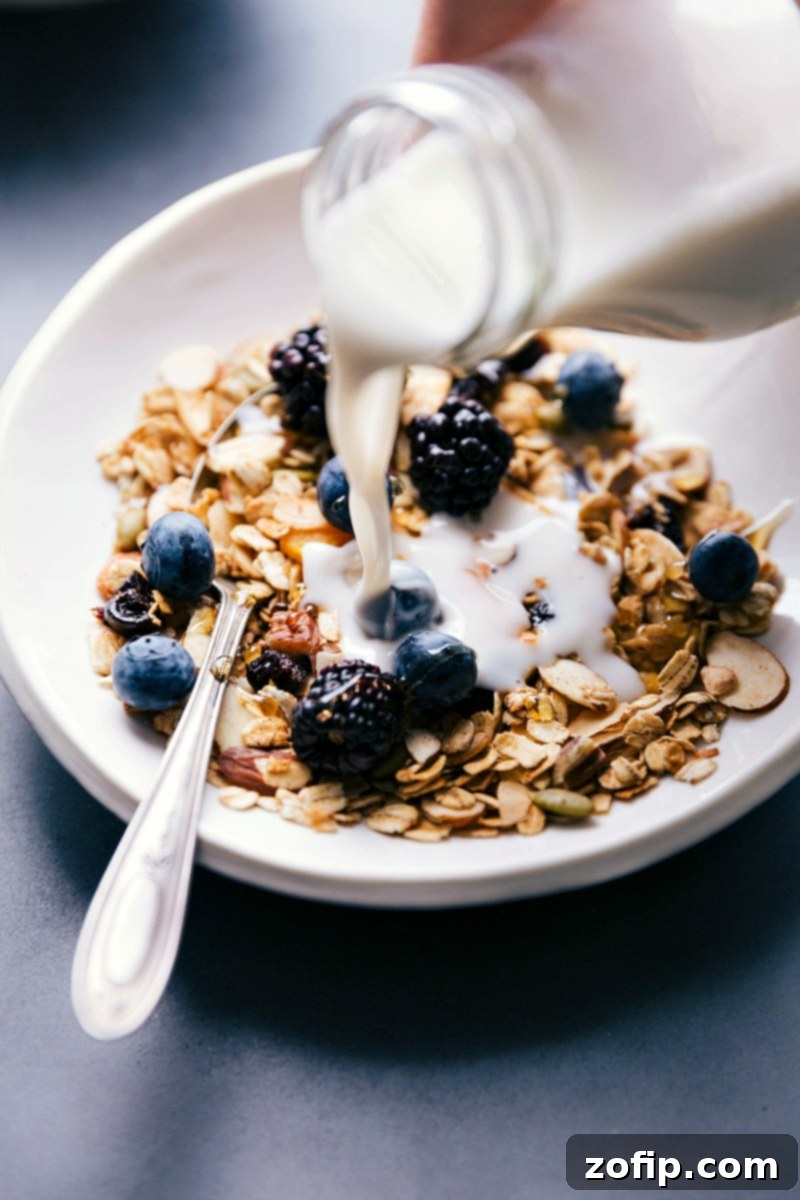 A stream of fresh milk being poured over a bowl of crunchy, homemade muesli, garnished with vibrant fresh berries, signifying a complete and wholesome breakfast dish.