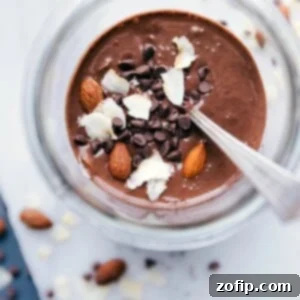 Almond joy overnight oats in a bowl, deliciously topped with almonds, shredded coconut, and chocolate chips.