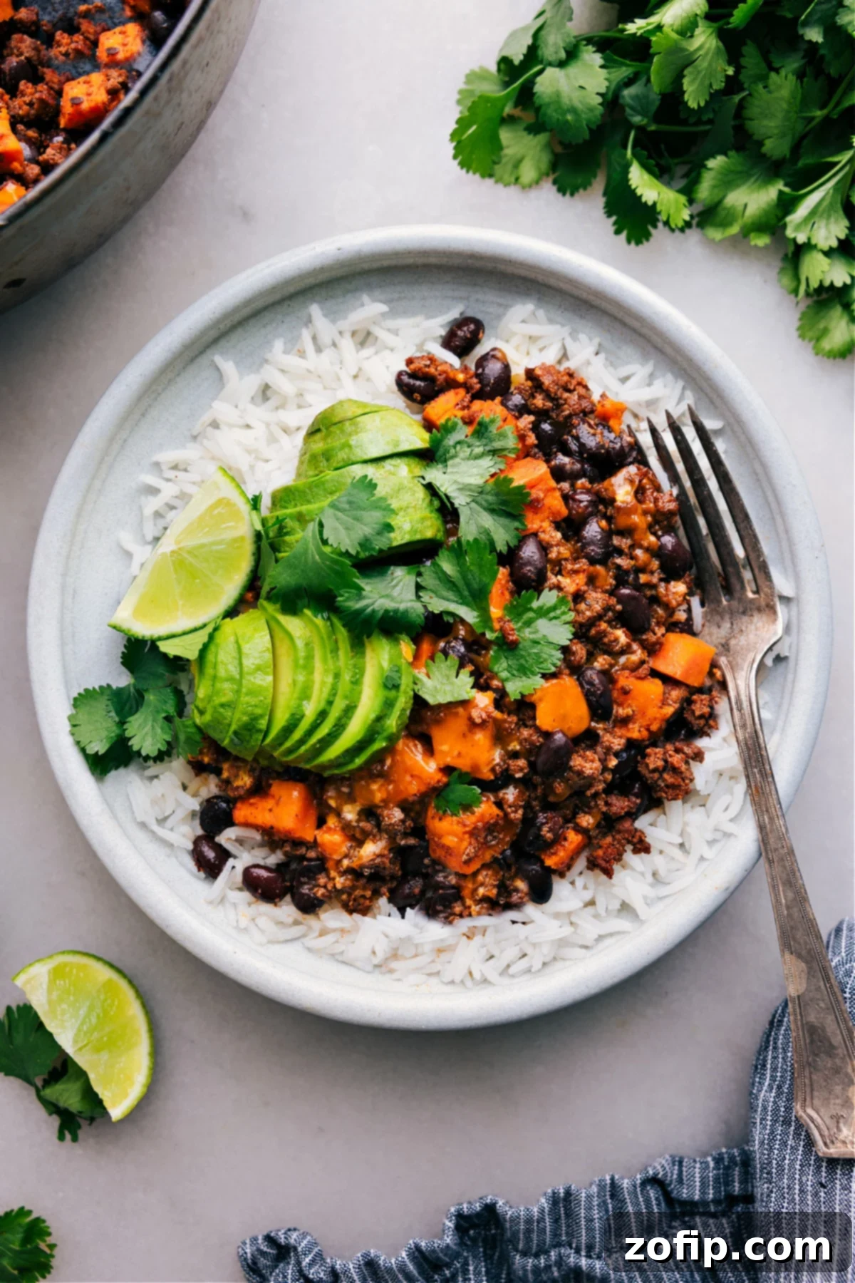 Ground Turkey Sweet Potato Skillet served beautifully on a plate of fluffy rice, with fresh avocado, vibrant cilantro, and a lime wedge ready on the side for a complete, wholesome meal.