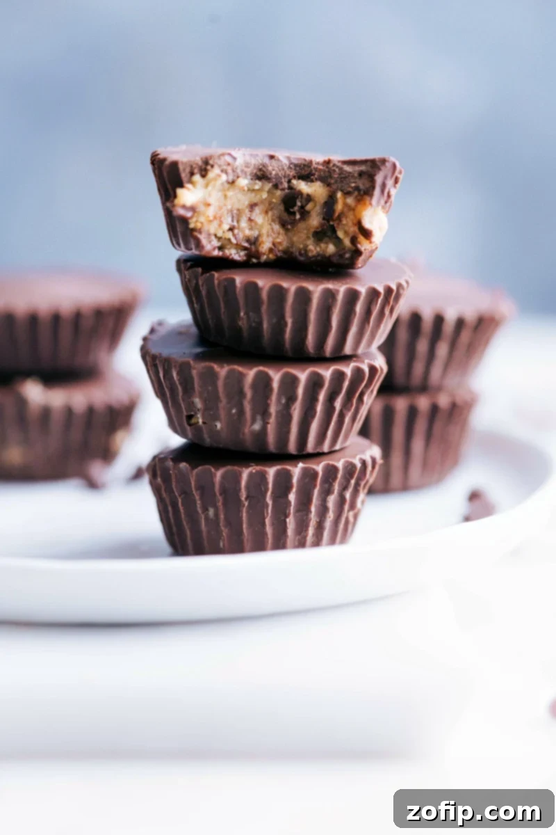 Photo of several Healthy Cookie Dough Cups stacked on a plate, showcasing their delicious dark chocolate coating and cookie dough center.