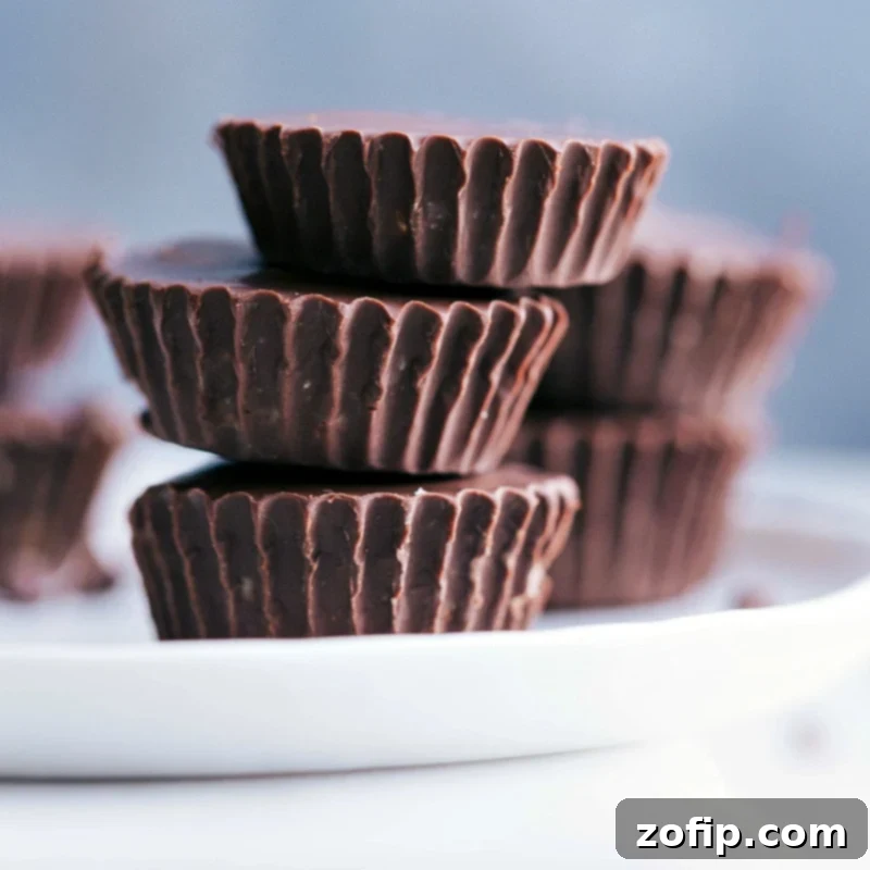 View of three Healthy Cookie Dough Cups stacked on a plate, showcasing the thick chocolate coating and the tempting cookie dough filling.