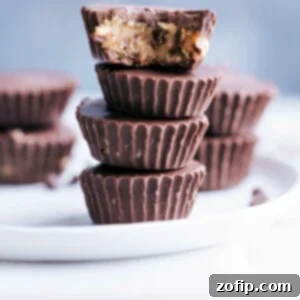 Close-up photo of a Healthy Cookie Dough Cup cut in half, showing the rich dark chocolate exterior and the creamy cashew-oat cookie dough filling.