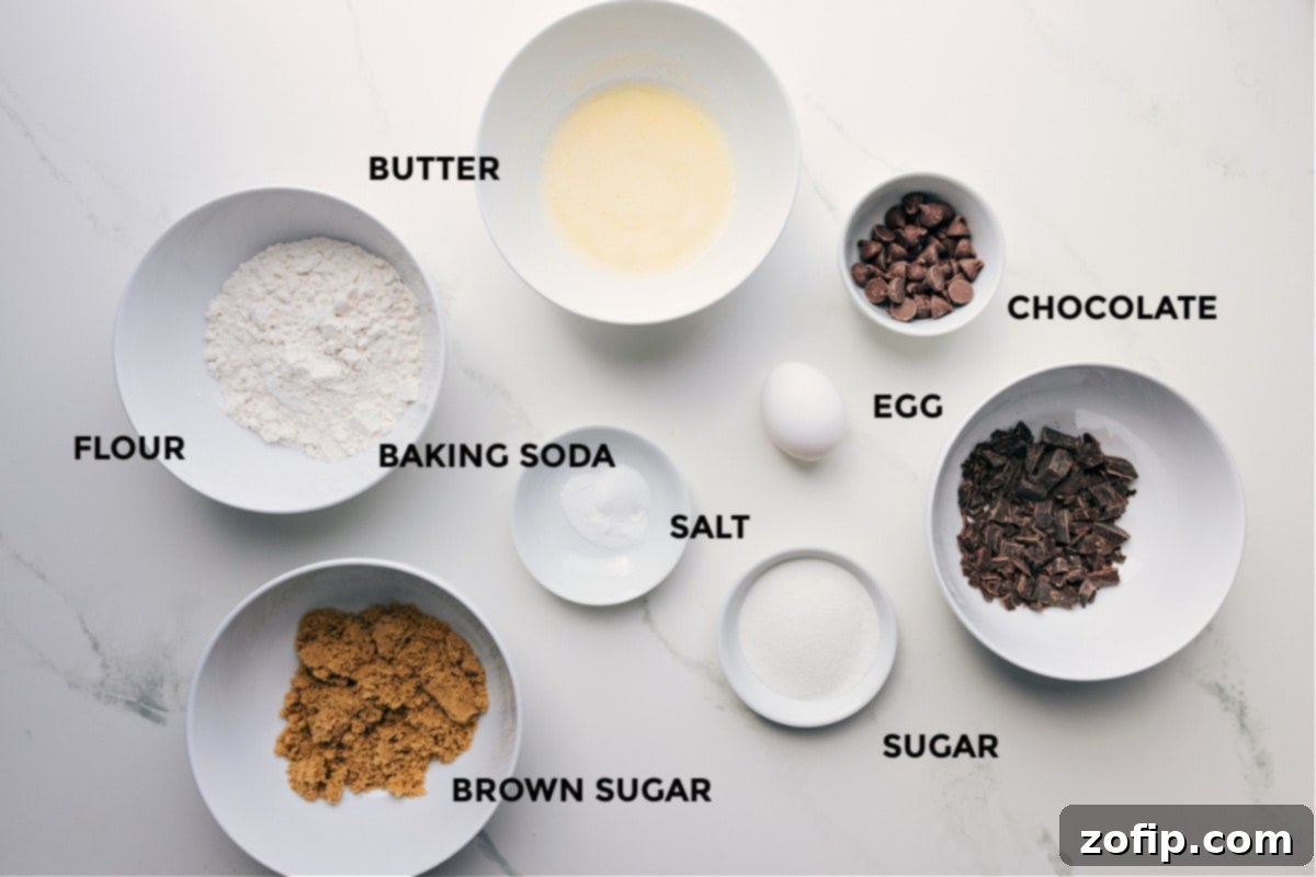 Ingredients prepped for easy assembly, including butter, flour, baking soda, chocolate, egg, sugar, and brown sugar, laid out on a clean surface.