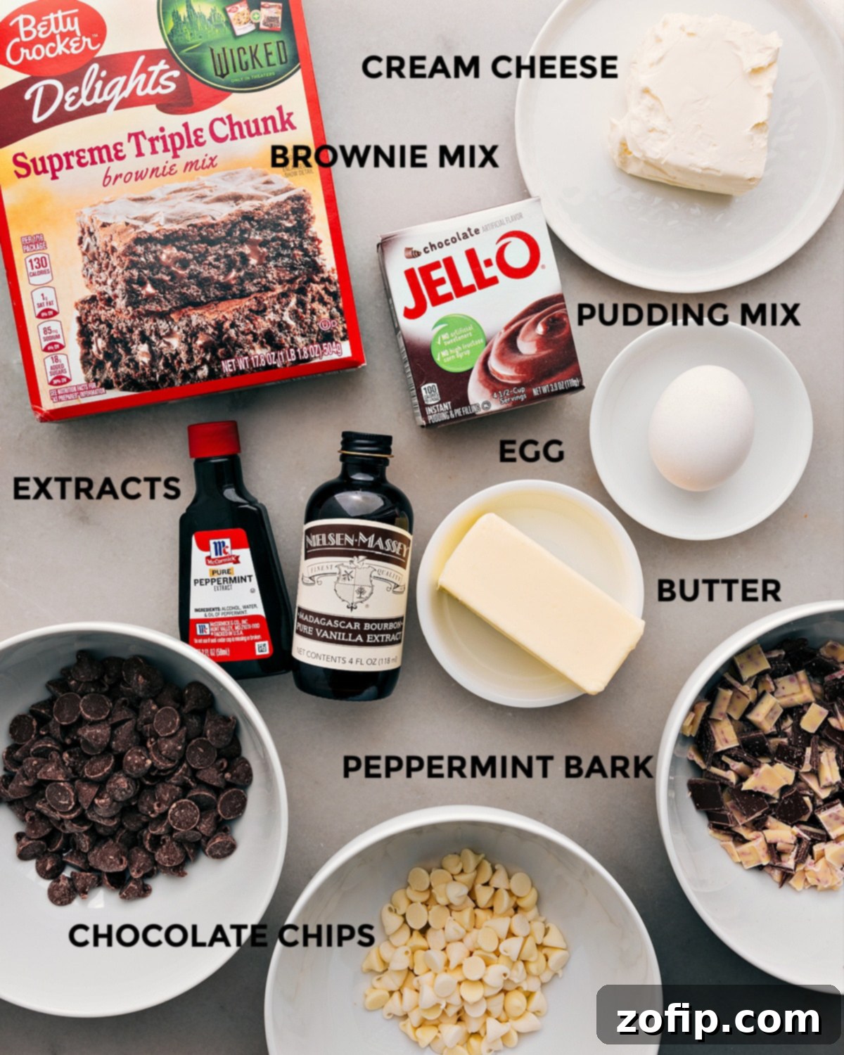 All the essential ingredients for making these delicious Chocolate Peppermint Cookies, including brownie mix, pudding mix, cream cheese, egg, butter, vanilla extract, peppermint extract, and various chocolate chips, neatly arranged on a countertop.