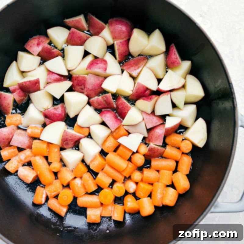 A healthy, fresh, and flavorful one-skillet meal featuring Lemon Chicken, Red Potatoes, and Carrots. Close-up of potatoes and carrots sautéing in a skillet, building flavor for the lemon chicken dish