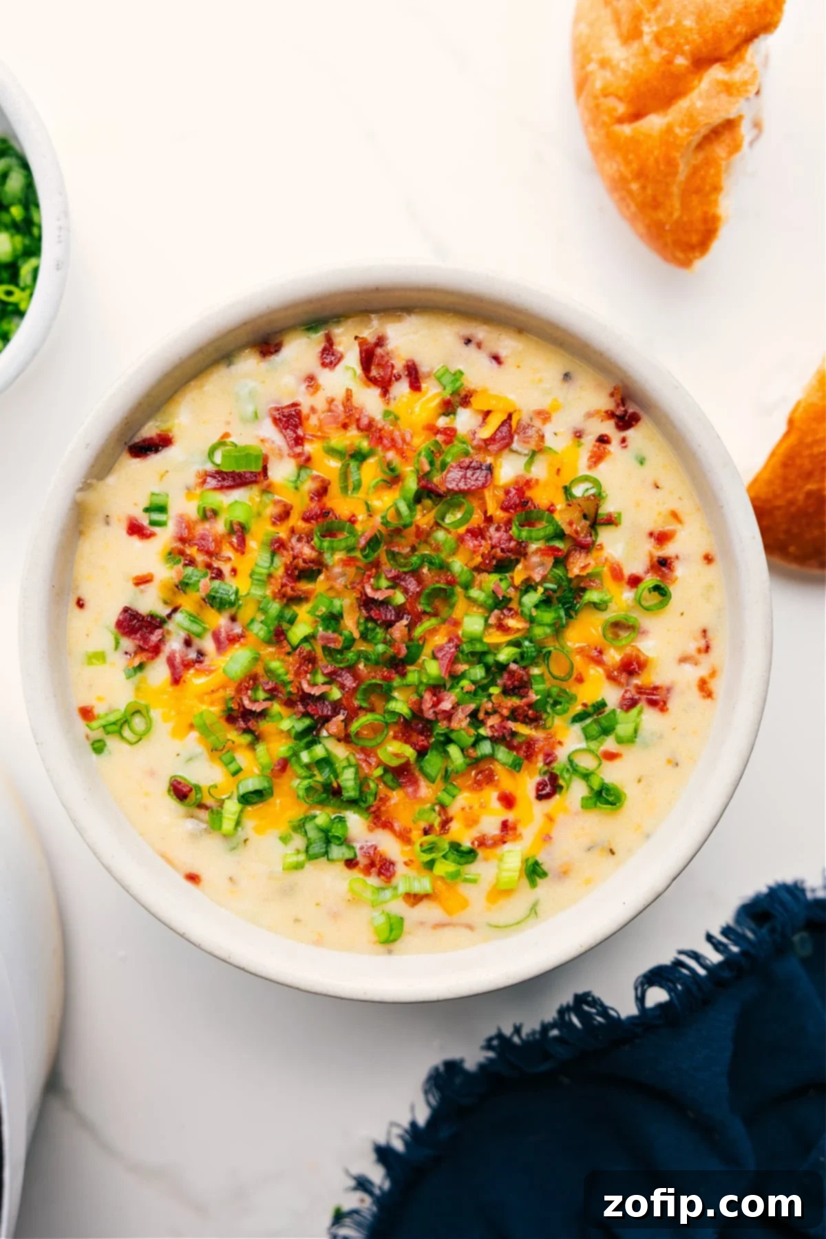 Loaded Potato Soup Recipe served in a bowl, topped with crispy bacon pieces and sliced green onions.