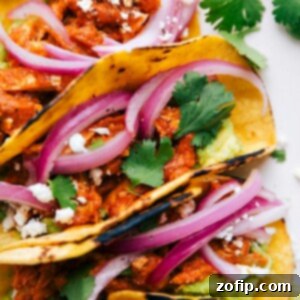 A fully assembled and stuffed meal, filled with pickled red onions, guacamole, and cilantro.