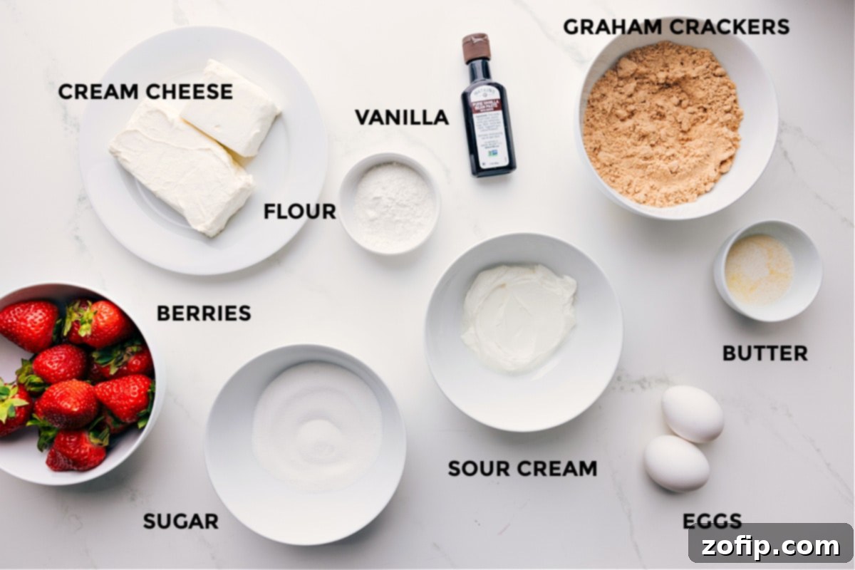 All the ingredients in this recipe prepped out for easy assembly including the berries, cream cheese, sugar, flour, vanilla, sour cream, eggs, butter, graham crackers, and vanilla.