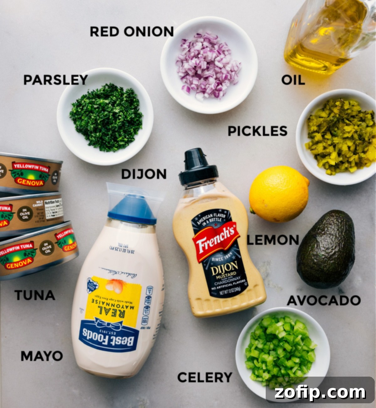 All the essential ingredients for Avocado Tuna Salad: canned tuna, fresh parsley, red onion, sweet pickles, olive oil, lemon, ripe avocado, Dijon mustard, mayonnaise, and crisp celery, beautifully prepped for an easy assembly.